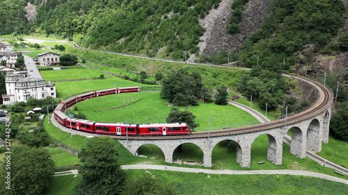 Aerial view of a Bernina Express train crossing the Brusio spiral viaduct of Rhaetian Railway, Grisons canton, Switzerland