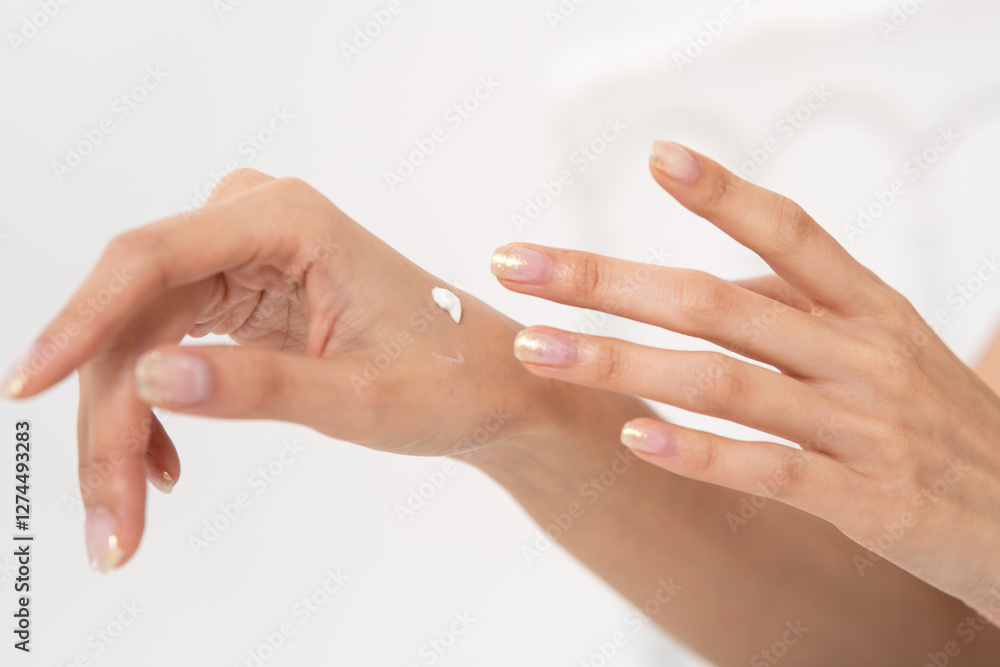 Fototapeta premium Beautiful Asian woman applying skincare product to her hand, showcasing beauty and self-care routine in a white background