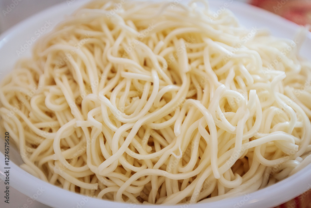 A close-up of freshly cooked noodles in a white bowl. The soft, slightly glossy texture highlights their perfect preparation, ready to be served or mixed with other ingredients. A close-up of freshly cooked noodles in a white bowl. The soft, slightly glossy texture highlights their perfect preparation, ready to be served or mixed with other ingredients.