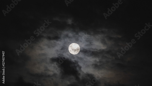 Dark black clouds covering full moon in the sky, frightful scenery