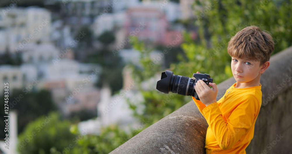 Fototapeta premium Cute boy with photo camera prepares to take pictures of Positano in Amalfi