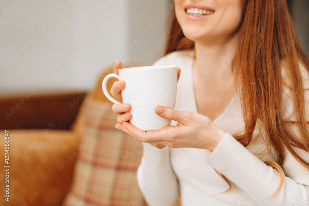 Woman enjoying a warm cup of coffee while smiling in a cozy living room setting Woman enjoying a warm cup of coffee while smiling in a cozy living room setting
