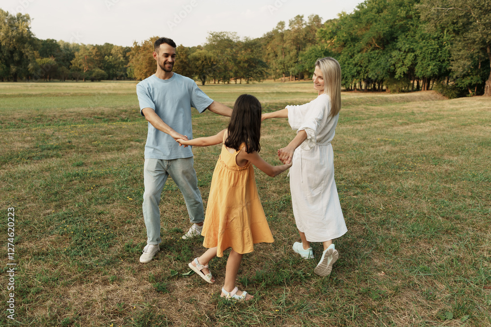 Family holding hands and playing joyfully in a beautiful green park. Family holding hands and playing joyfully in a beautiful green park.