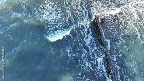 Wallpaper Mural A breakwater made of large stones stretches into clear blue waters providing protection to the shore Sunlight reflects off the gentle waves creating a peaceful coastal atmosphere Torontodigital.ca