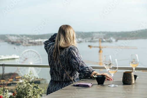 Woman with wine overlooking city harbor 