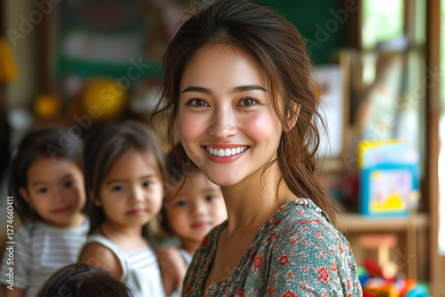 Smiling young nanny with dark hair stands in a bright and cozy daycare surrounded by happy children, creating a warm and caring atmosphere of trust and learning