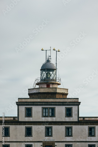 Historic Faro de Finisterre lighthouse against a cloudy sky photo