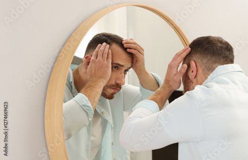 Εκτύπωση καμβά Baldness problem. Man with receding hairline near mirror at home