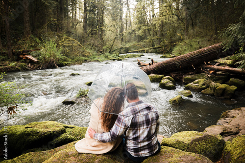 Romantic couple at streams edge in a rainy Pacific Northwest forest