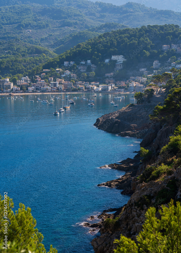 Fototapeta premium Scenic view of Port de Soller Bay with numerous yachts, boats anchored in turquoise waters. Picturesque Mediterranean coastal scene surrounded mountains, charming waterfront buildings