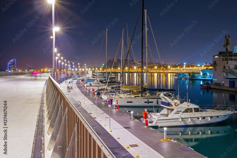 Barcelona Marina at night shines with city lights reflecting on the water, featuring elegant yachts, a vibrant atmosphere, and stunning views of the Mediterranean coast
