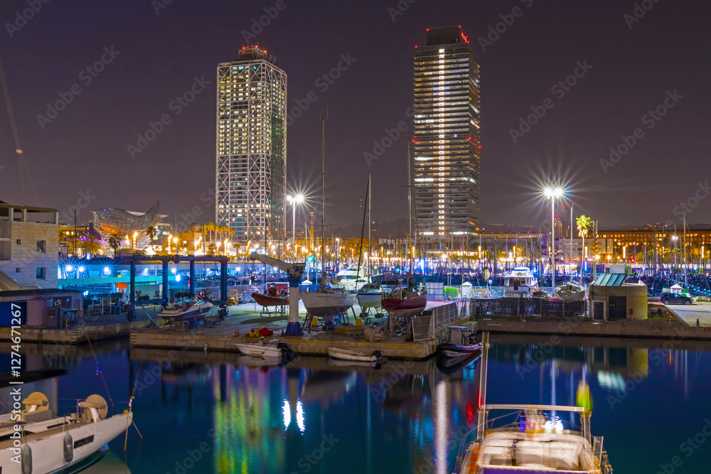 Barcelona Marina at night shines with city lights reflecting on the water, featuring elegant yachts, a vibrant atmosphere, and stunning views of the Mediterranean coast