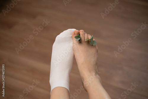 Bare Foot with Eucalyptus Leaves and White Sock on Wooden Floor photo