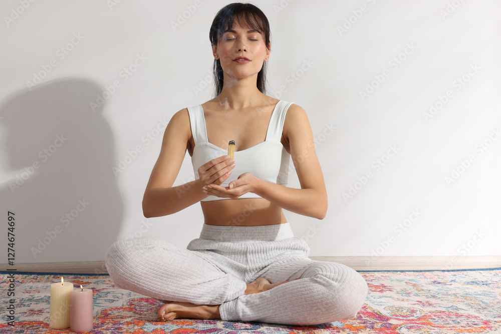 Woman with smoldering palo santo stick on floor at home Woman with smoldering palo santo stick on floor at home