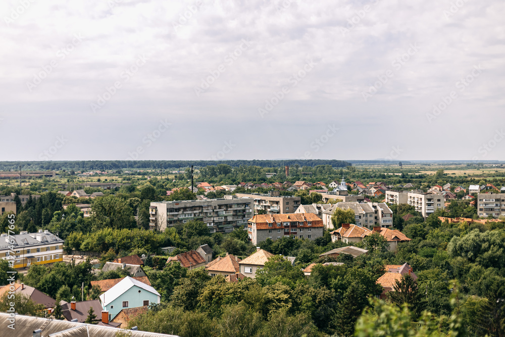 Scenic vista showcasing a cityscape nestled amidst lush greenery, with rolling hills stretching into the distance under a cloudy sky, offering a tranquil and picturesque view Scenic vista showcasing a cityscape nestled amidst lush greenery, with rolling hills stretching into the distance under a cloudy sky, offering a tranquil and picturesque view