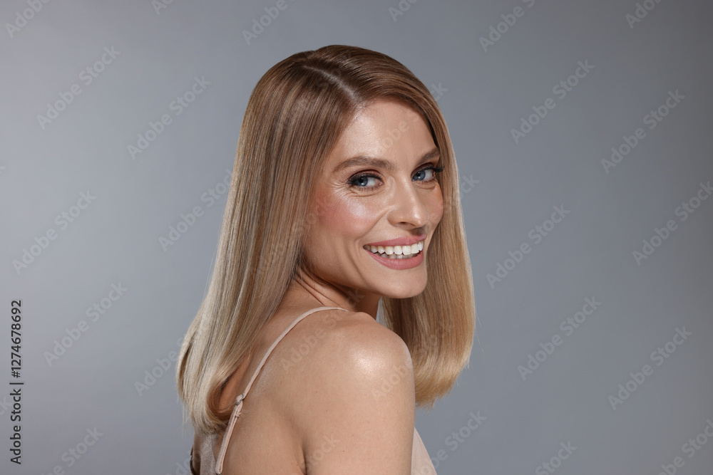 Fototapeta premium Portrait of beautiful happy woman with straight blonde hair on grey background