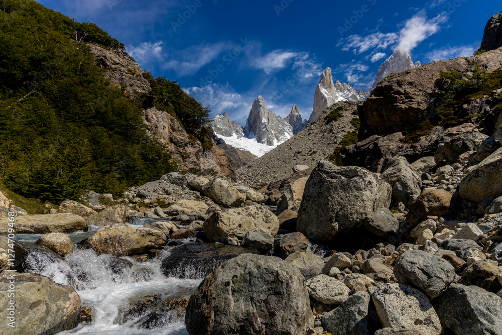 Fototapeta premium Fitz Roy sharp mountain peaks rise above a serene glacial lake, surrounded by rugged terrain snow-covered slopes in Patagonia, Argentina, El Chalten. Fitzroy mountain granite peak laguna de Los Tres