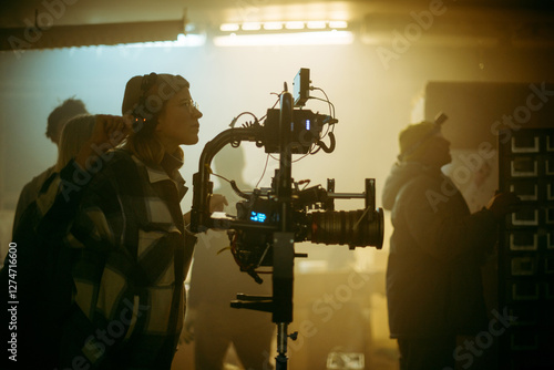 The director of photography is a woman behind a video camera on the set. A professional videographer at work on the filming of a movie, commercial or TV series. Filming process indoors, studio