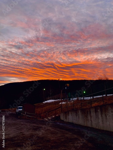 The sky burns in orange and pink tones at sunset, contrasting with the dark silhouette of the mountain