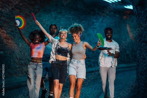 Canvas Print Friends walking and waving rainbow hand fans at night festival celebrating toget