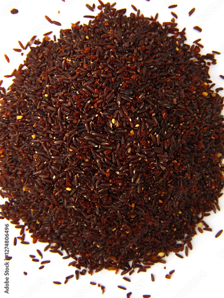 Pile of dark brown unprocessed rice grains with a reddish hue scattered on a white background viewed from above. Pile of dark brown unprocessed rice grains with a reddish hue scattered on a white background viewed from above.