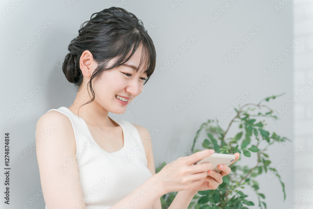 家で動画を見る・スマホゲームをするリラックスしたアジア人女性
