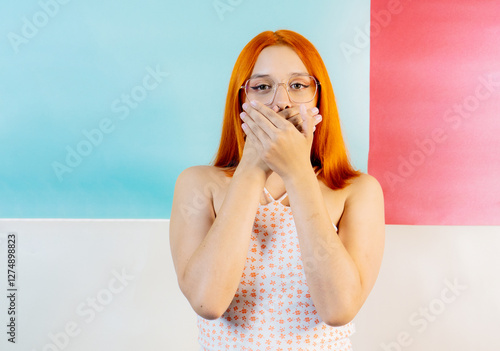 foto de studio de mujer mirando a cámara tapando su boca con las manos - foto de stock 