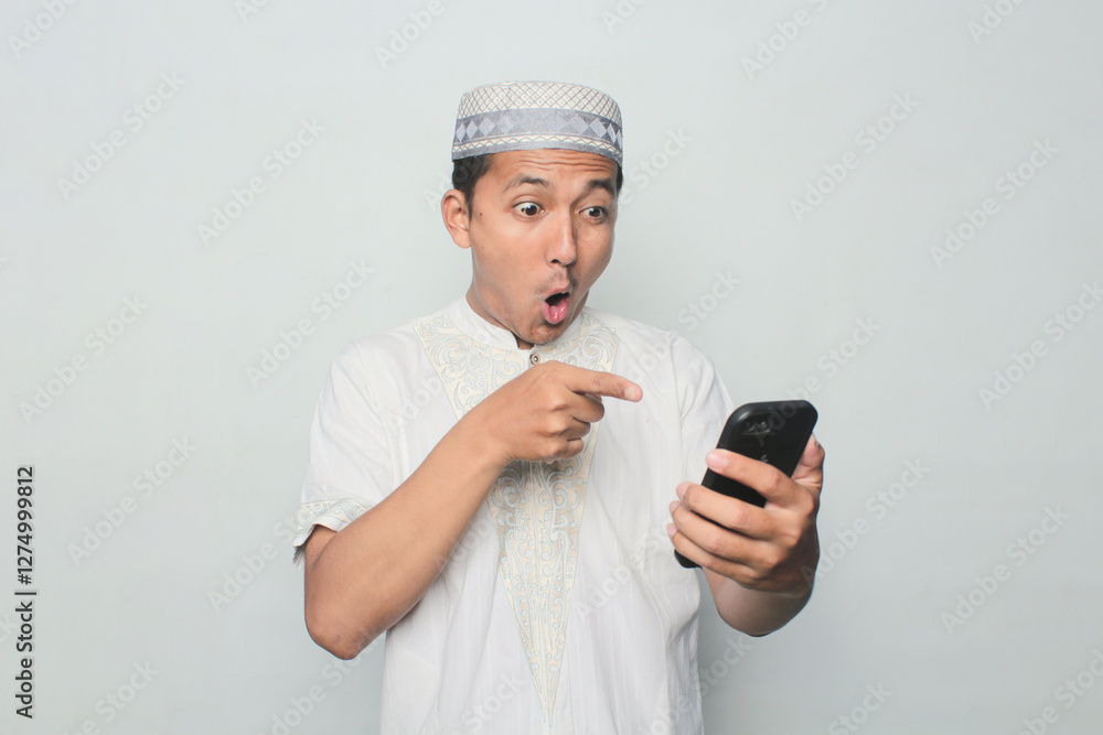 Asian Muslim man is playing with a smartphone with a white background. Asian Muslim man is playing with a smartphone with a white background.