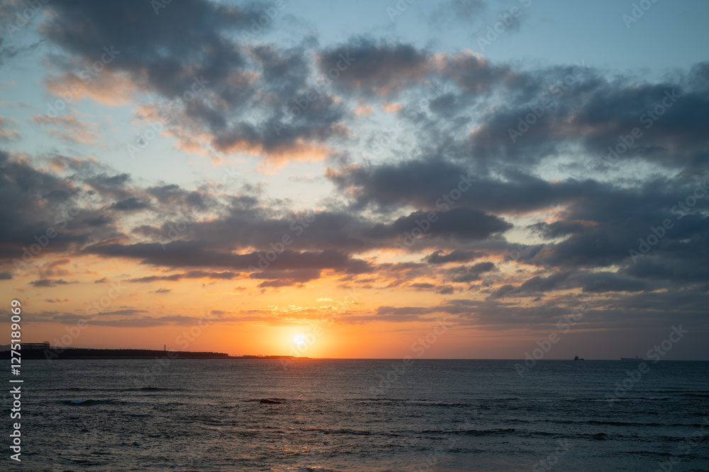 Fototapeta premium A stunning sunset over Tamsui Beach with vibrant pink and purple hues in the sky. The calm sea reflects the colorful sky, creating a serene atmosphere. Tamsui, Taiwan.