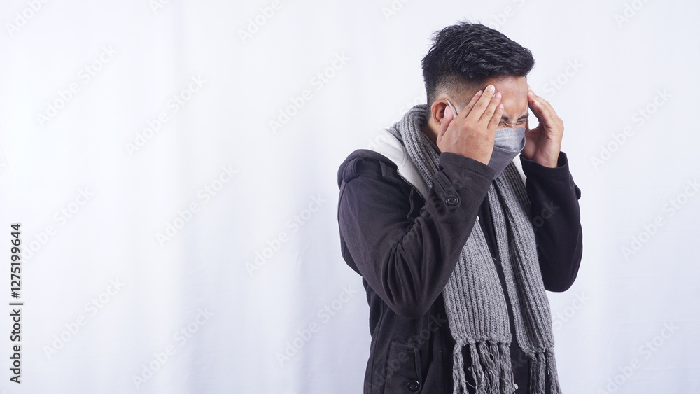 Side View of Asian Man Wearing Jacket, Scarf, and Mask Suffering from Bad Headache Isolated on White Background Side View of Asian Man Wearing Jacket, Scarf, and Mask Suffering from Bad Headache Isolated on White Background