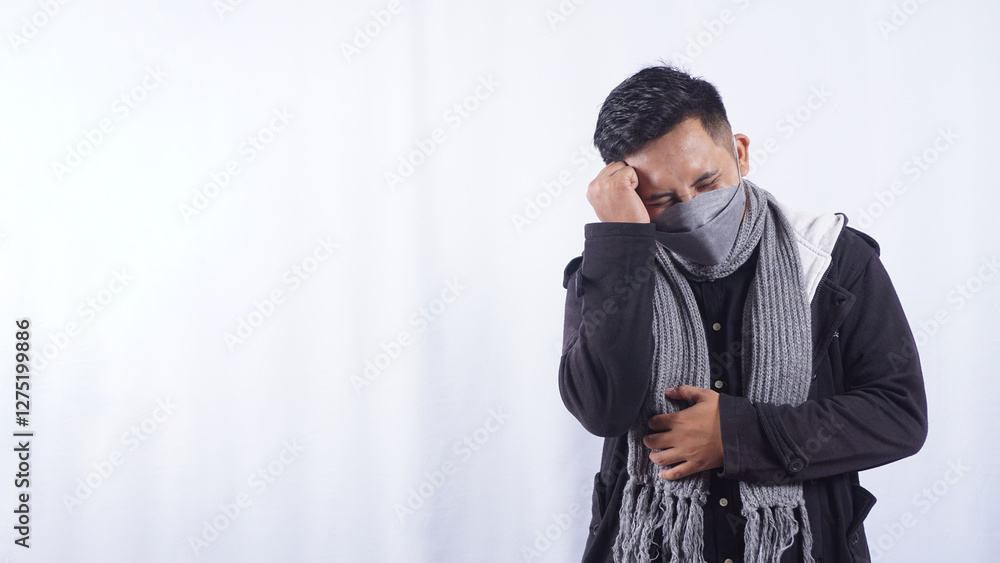 Asian Man Wearing Jacket, Scarf, and Mask Touching Head Suffering from Bad Headache Isolated on White Background Asian Man Wearing Jacket, Scarf, and Mask Touching Head Suffering from Bad Headache Isolated on White Background