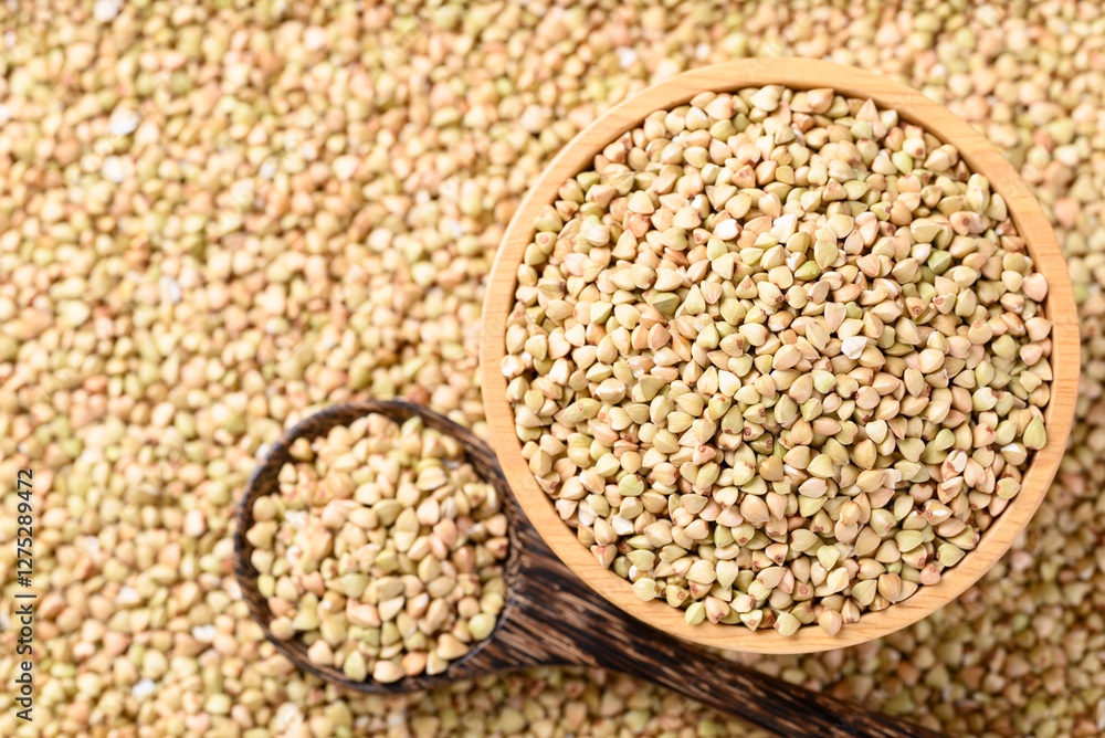 Organic buckwheat seed in wooden bowl with spoon on buckwheat background, Food ingredient Organic buckwheat seed in wooden bowl with spoon on buckwheat background, Food ingredient