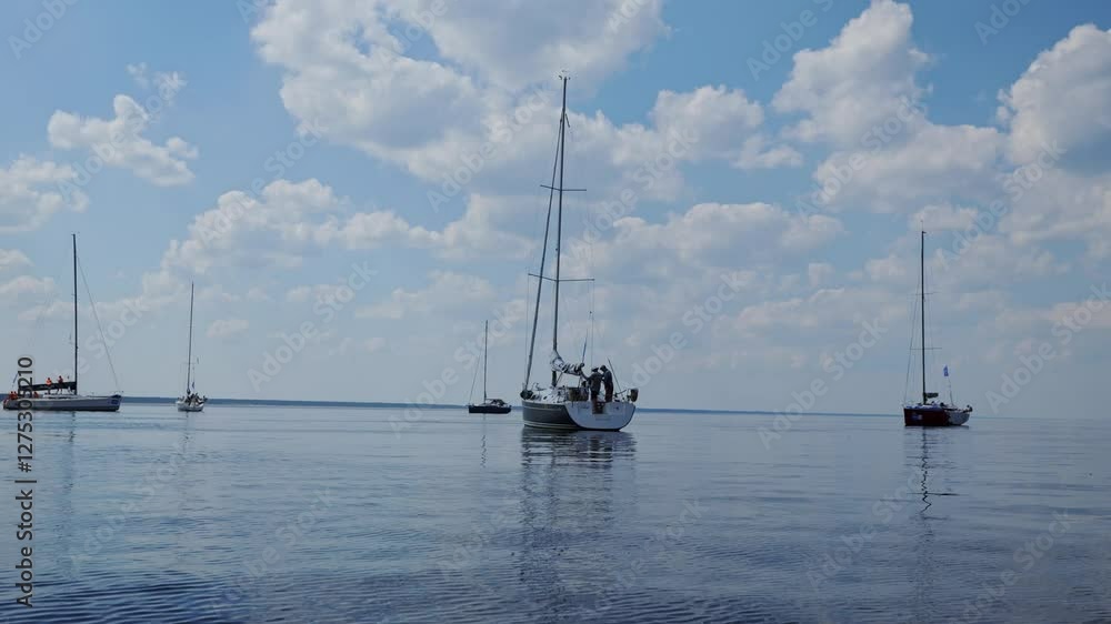 A peaceful sailing scene with boats resting on the water under a vast open sky