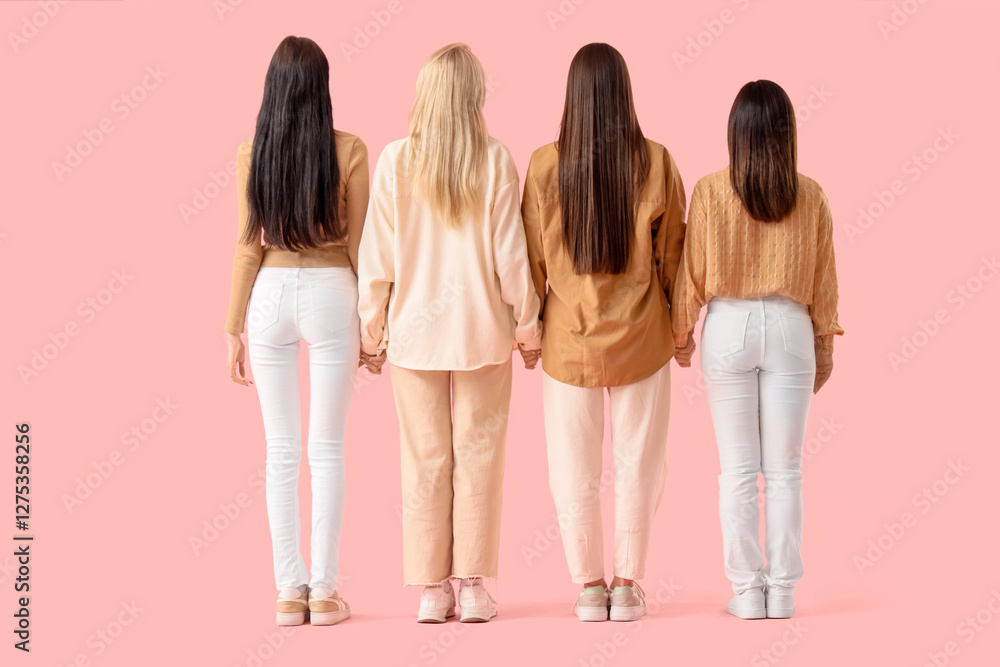 Naklejka premium Group of young women holding hands on pink background, back view. Women's History Month