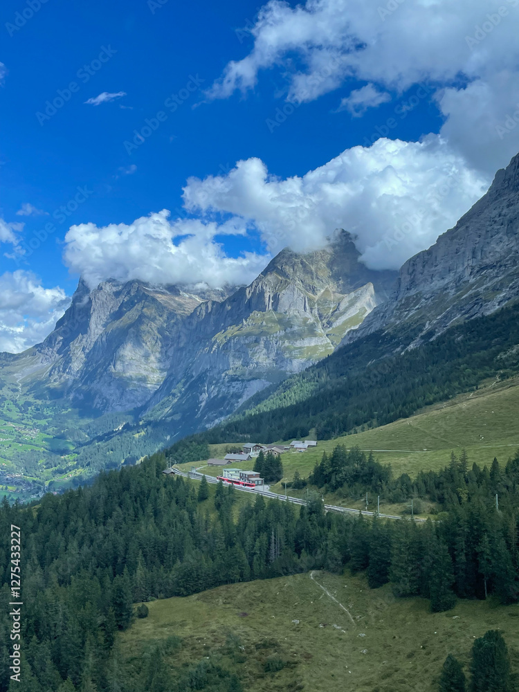 Fototapeta premium Scenic Swiss Mountain Landscape with Red Train Winding Through Green Valleys and Forests – Travel Photography