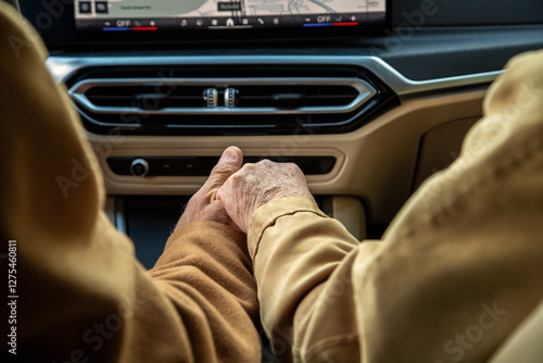 An elderly coupld holding hands in their electric vehicle photo