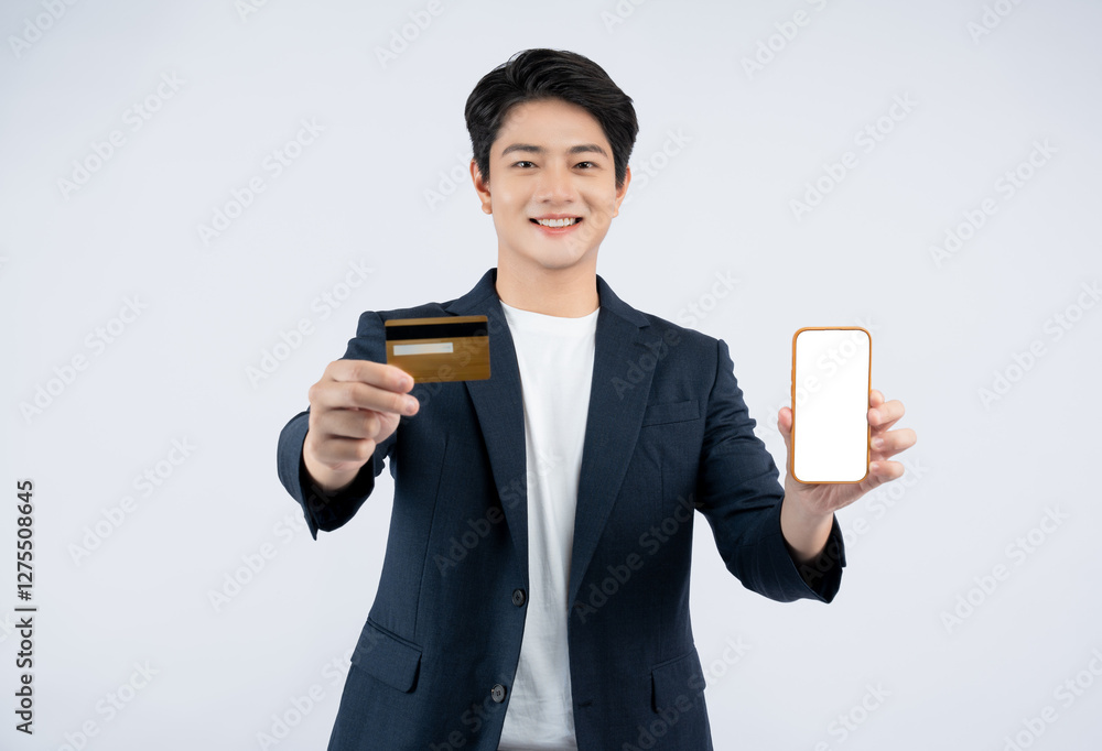 Portrait of young Asian business man holding bank card and using phone posing on white background Portrait of young Asian business man holding bank card and using phone posing on white background