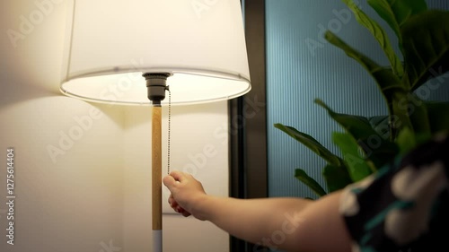 Hand of woman reaching out to turn on a lamp in the living room at a cozy home, A calm and inviting atmosphere, Hand pulling chain of lamp