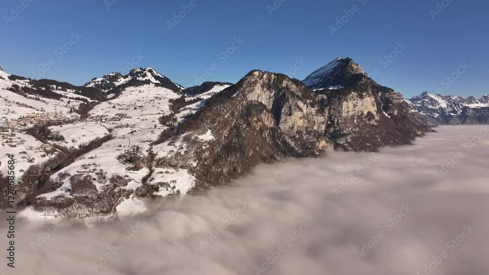 Aerial view of a breathtaking sea of fog blanketing the stunning Wallensee in Switzerland, with snow-capped mountains rising above the clouds. Aerial view of a breathtaking sea of fog blanketing the stunning Wallensee in Switzerland, with snow-capped mountains rising above the clouds.
