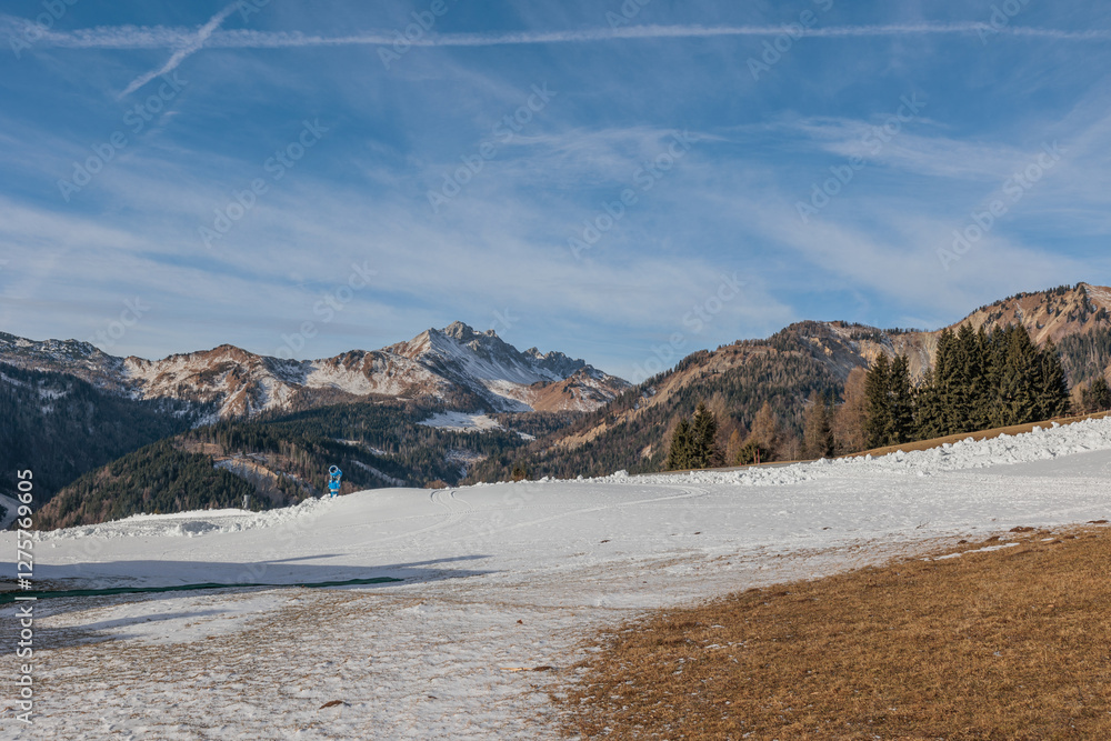 panoramica su un ambiente naturale tra le montagne del nord Italia, parzialmente innevato, di giorno, in inverno, con cielo sereno, leggermente nuvoloso