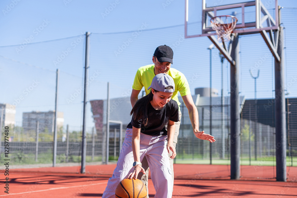 Obraz premium Father and teenage daughter playing basketball outside at court
