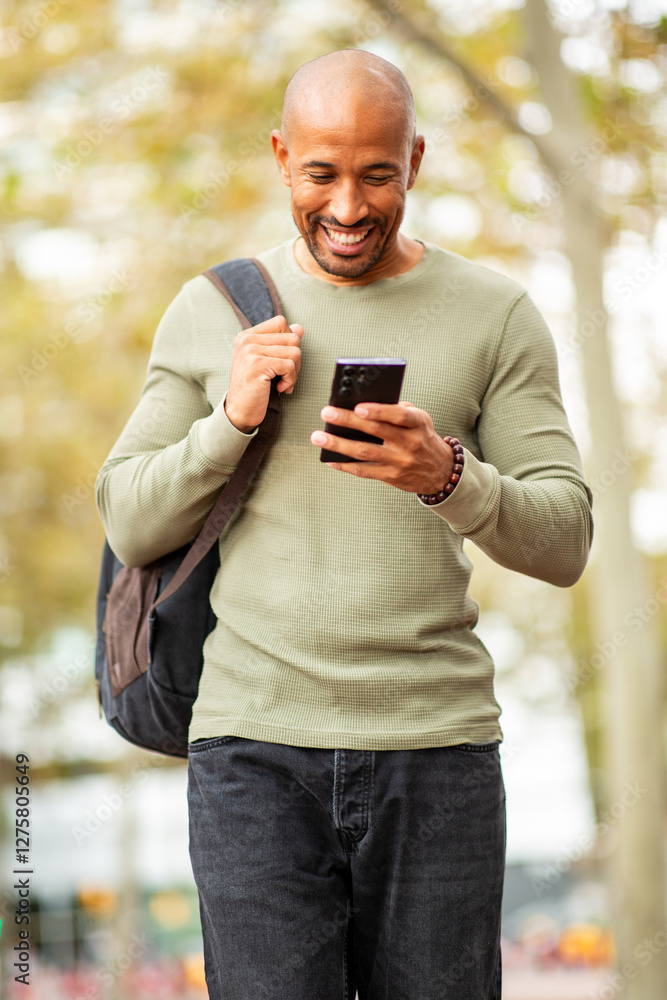Smiling bald man looking at mobile phone outdoors Smiling bald man looking at mobile phone outdoors