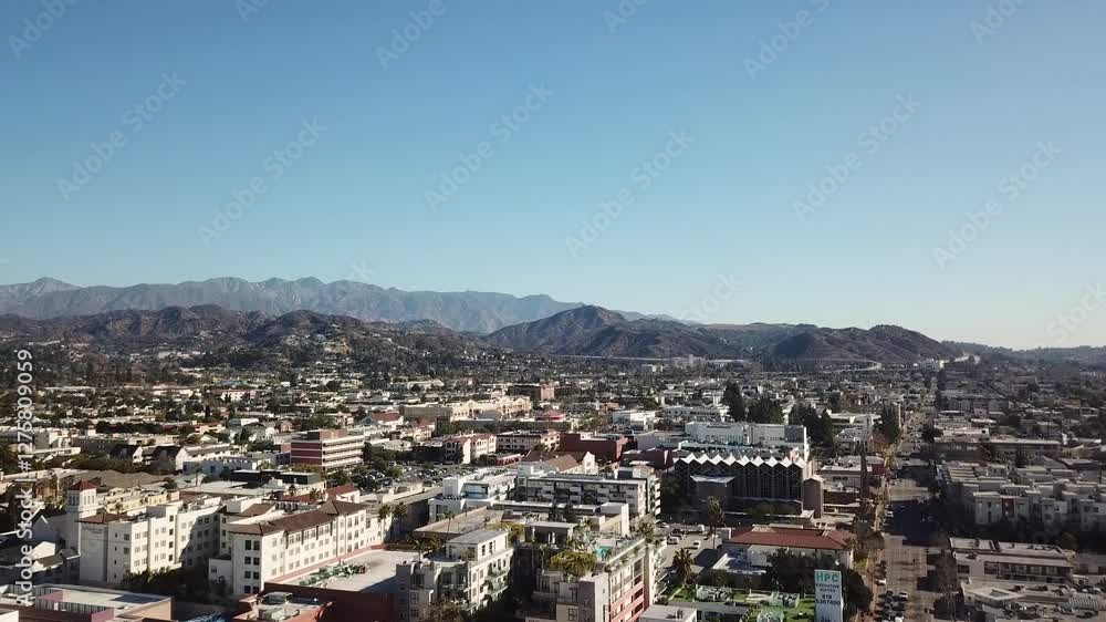 Drone rising shot of housing area in downtown with mountain range in distance. Blue sky and sunny day in american town. California, America. Apartment blocks in modern style. Drone rising shot of housing area in downtown with mountain range in distance. Blue sky and sunny day in american town. California, America. Apartment blocks in modern style.