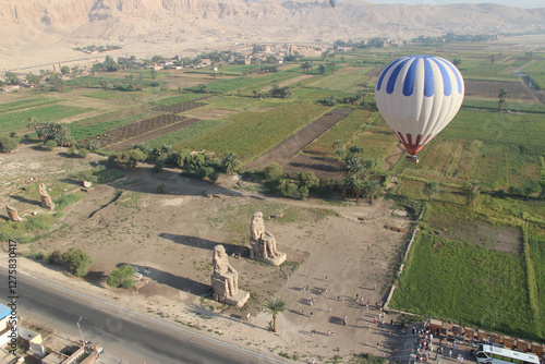 Aerial view of the Colossi of Memnon and hot air balloon in the morning, Luxor, Egypt