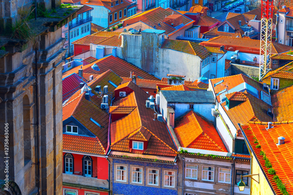 Vibrant rooftops of European city with colorful facades and terracotta tiles under sunlight. Mix of traditional and modern architecture creates picturesque urban landscape full of charm and character