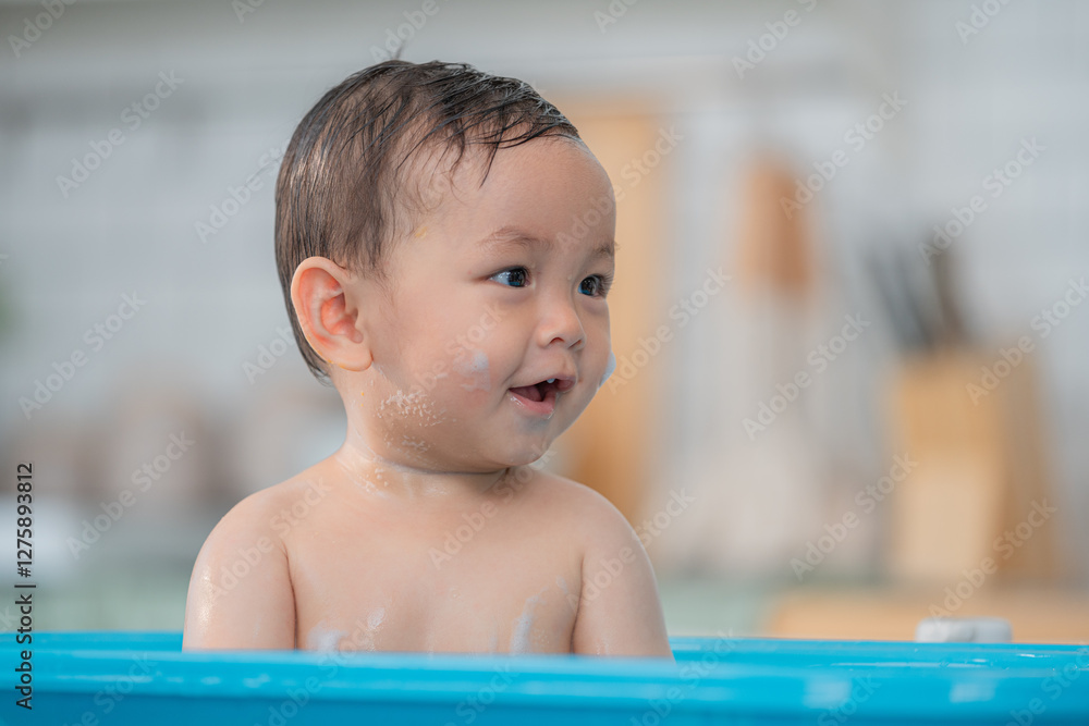 Smiling toddler enjoying bath time in a bright kitchen on a sunny day Smiling toddler enjoying bath time in a bright kitchen on a sunny day
