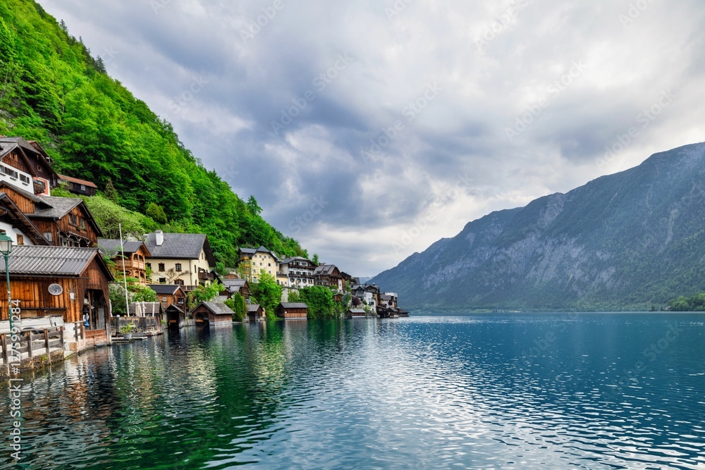 View of Hallstatt, Austria with charming lakeside houses and lush green mountains under a cloudy sky View of Hallstatt, Austria with charming lakeside houses and lush green mountains under a cloudy sky