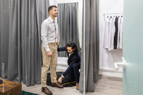 Tailor measuring man for clothing adjustments in a suit store