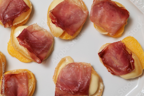 Obraz na płótnie dettaglio di un piatto visto dall'alto con degli antipasti a base di fette rotonde di polenta, scamorza affumicata e prosciutto crudo w salonie