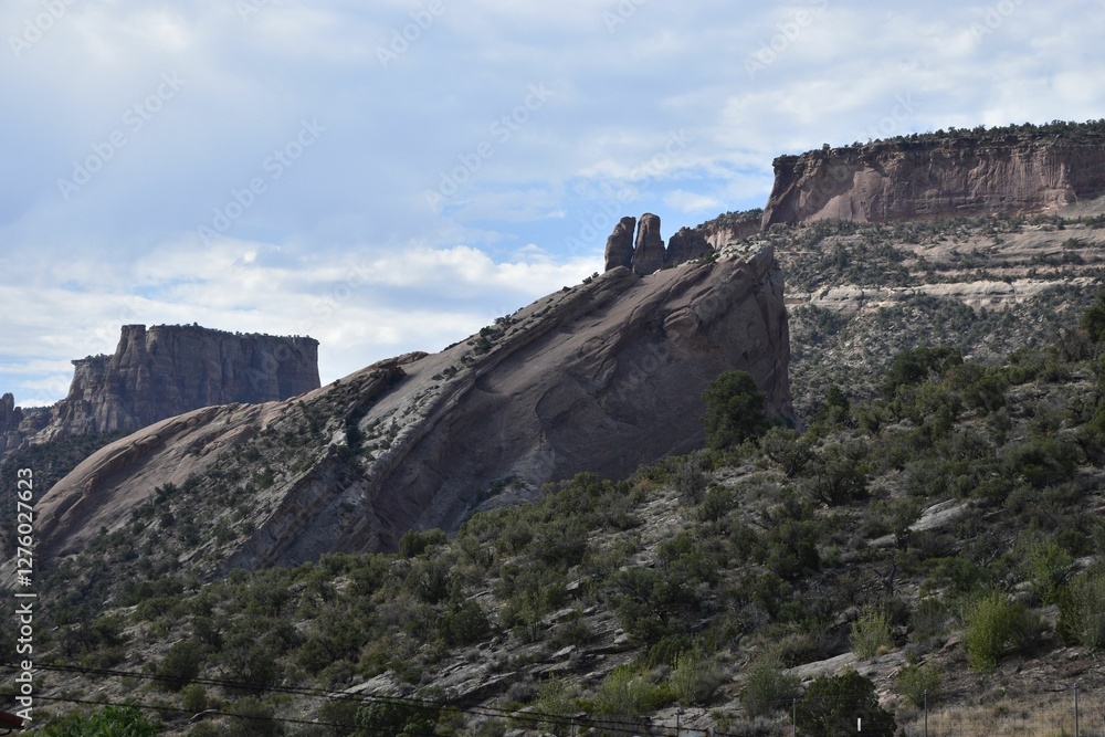 Rugged rock formations and greenery under a partly cloudy sky in Colorado National Monument. Rugged rock formations and greenery under a partly cloudy sky in Colorado National Monument.
